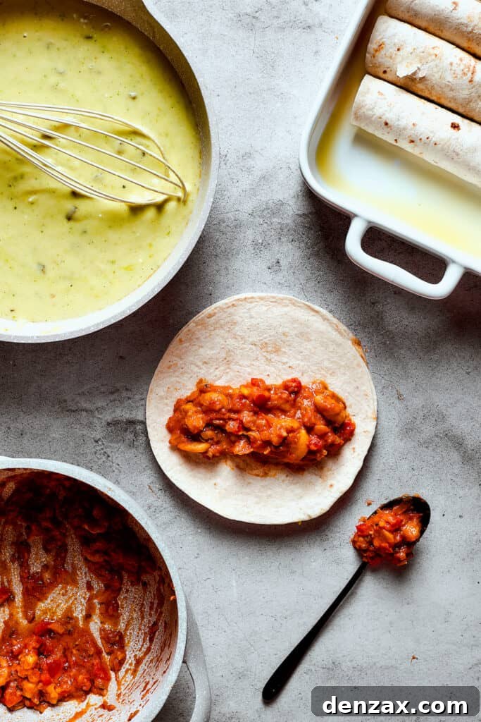 A baking dish with enchiladas in it. One tortilla is on the work surface with shrimp filling arranged down the center, ready to be rolled.
