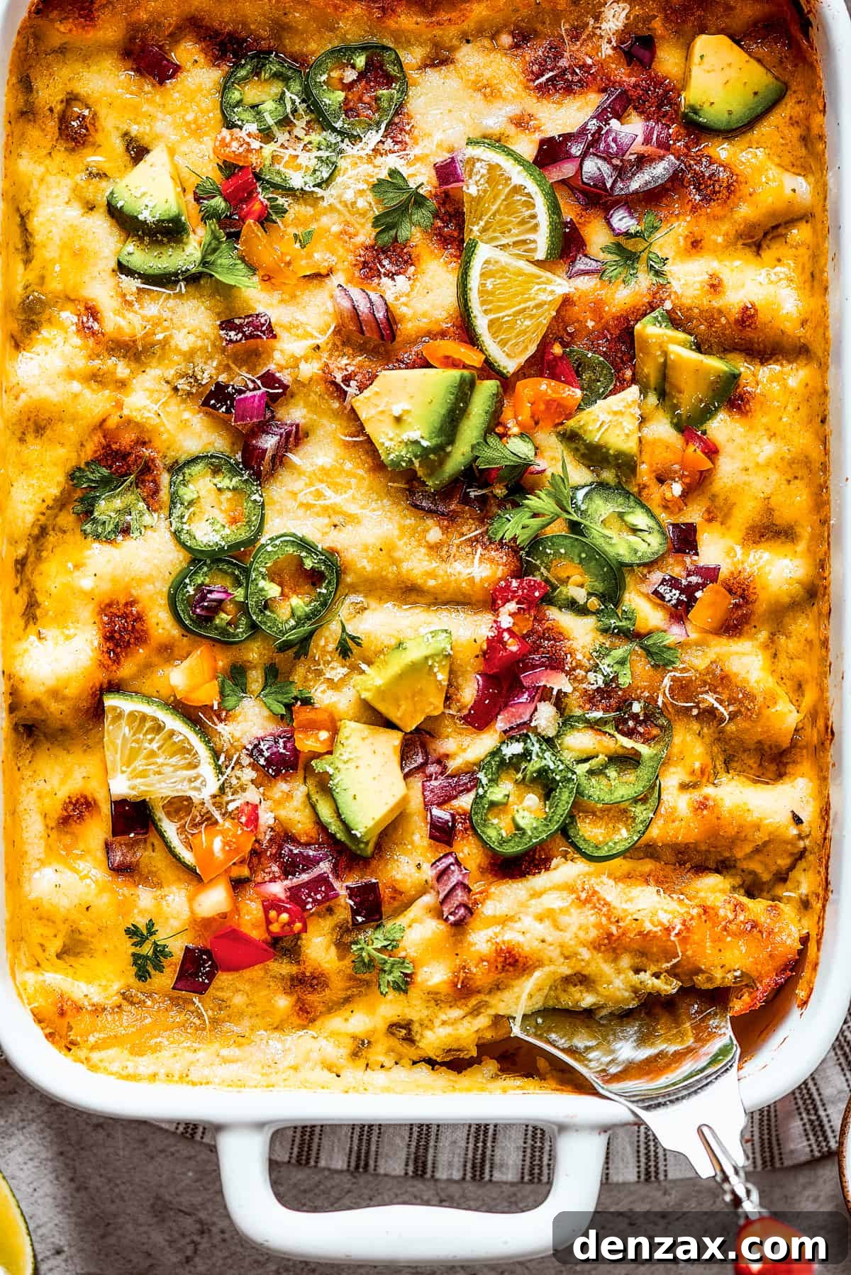 Photo of the bottom corner of a baking dish of homemade shrimp enchiladas, showing a bubbling, cheesy surface.