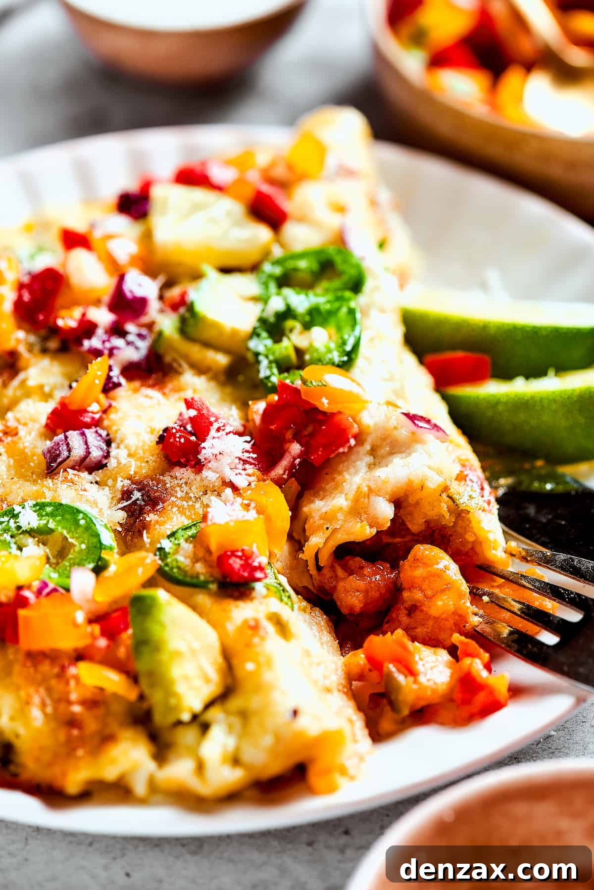 A plate of enchiladas topped with avocado, cilantro, and pico de gallo, ready to be enjoyed.