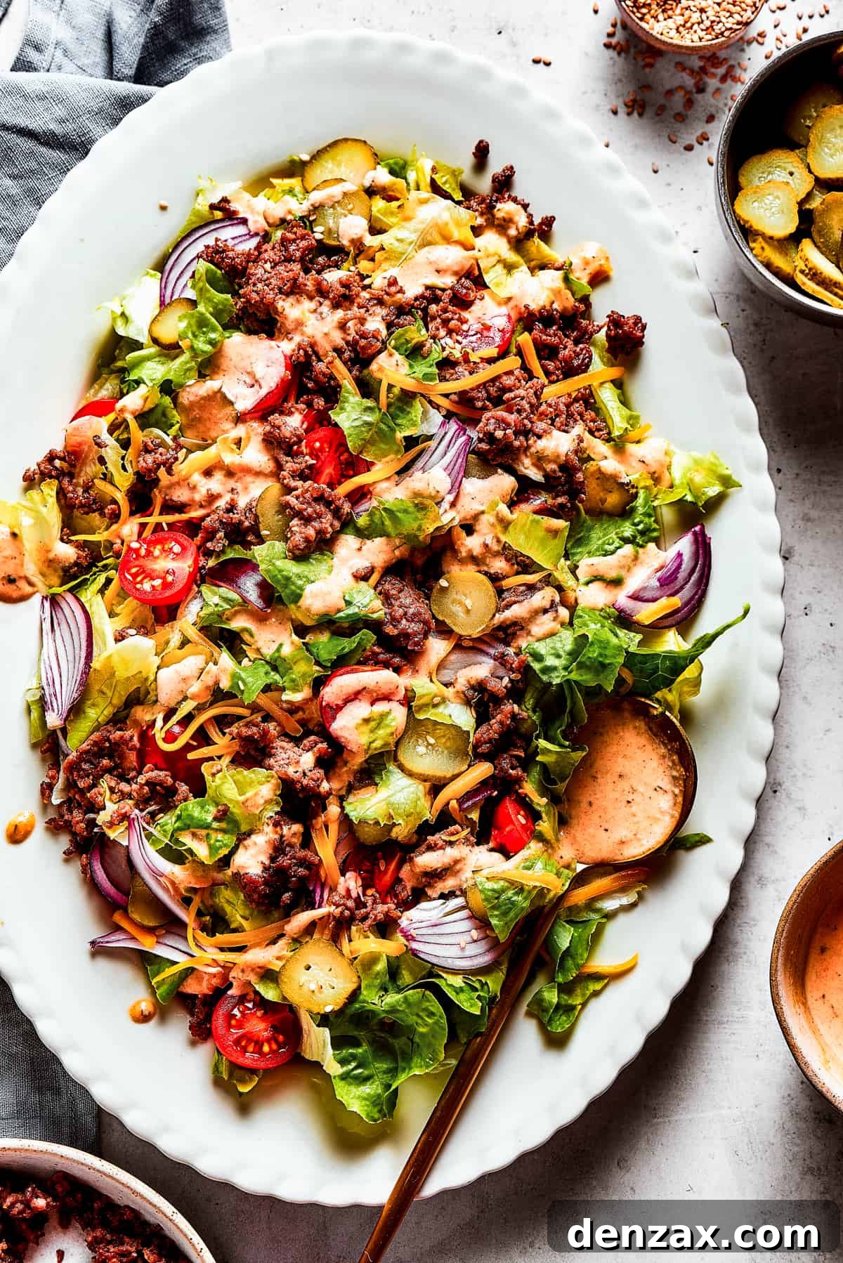 Overhead image of a Big Mac salad served on an oval white platter, showcasing fresh ingredients and a rich dressing.