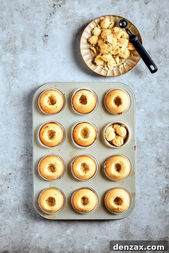 Cooled cupcakes in a pan with their centers neatly cored out, ready for filling with banana pudding.