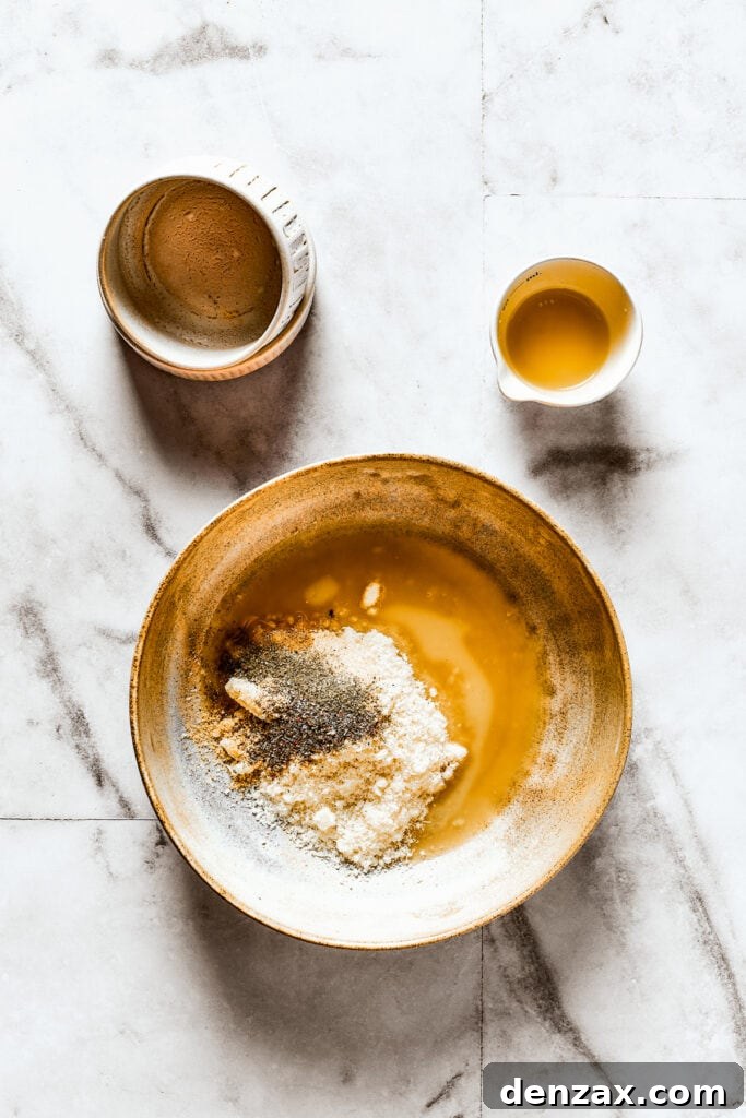 A shallow dish containing melted butter, parmesan, and a blend of seasonings.