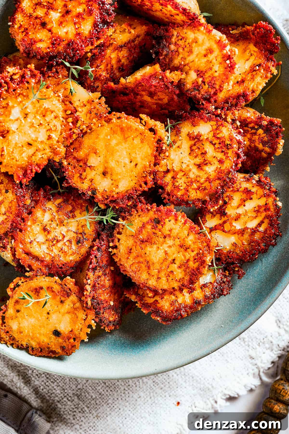 Close-up of a serving of Parmesan-crusted potatoes in a bowl, showing the crispy texture.