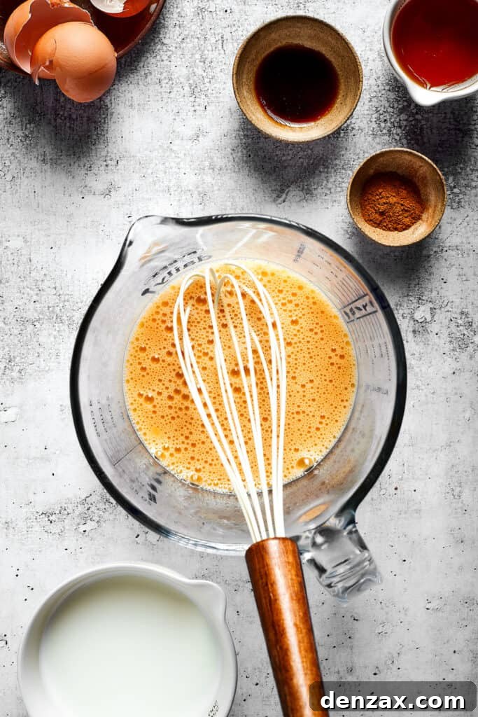 A pyrex with an egg and milk mixture with a whisk in it, next to some bowls