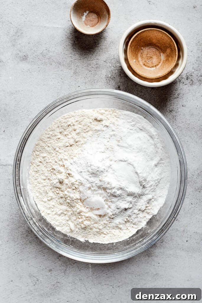 A mixing bowl filled with a combined flour mixture, surrounded by small, empty ingredient bowls.