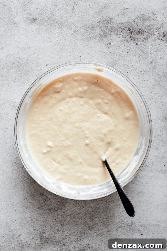 A mixing bowl containing biscuit dough, with a spoon resting in it, showing a uniform mixture.