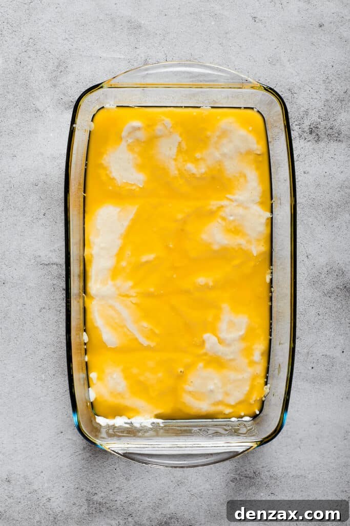 Biscuit dough carefully poured into a baking dish already containing melted butter, ready for baking.