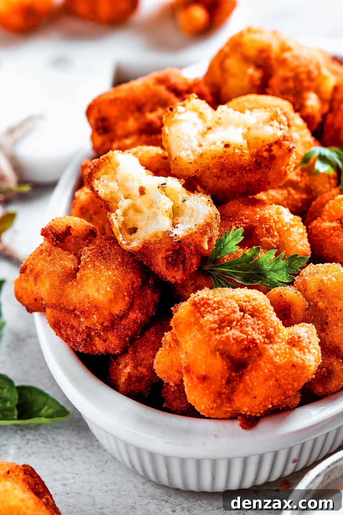 A beautiful serving bowl brimming with golden fried mac and cheese bites, surrounded by more individually prepared mac and cheese balls, all ready to be enjoyed.