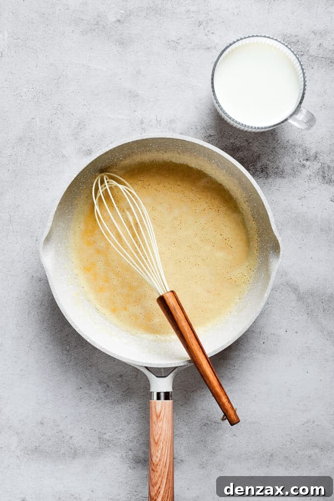 A saucepan on a stovetop containing a freshly prepared roux, being whisked to perfection.