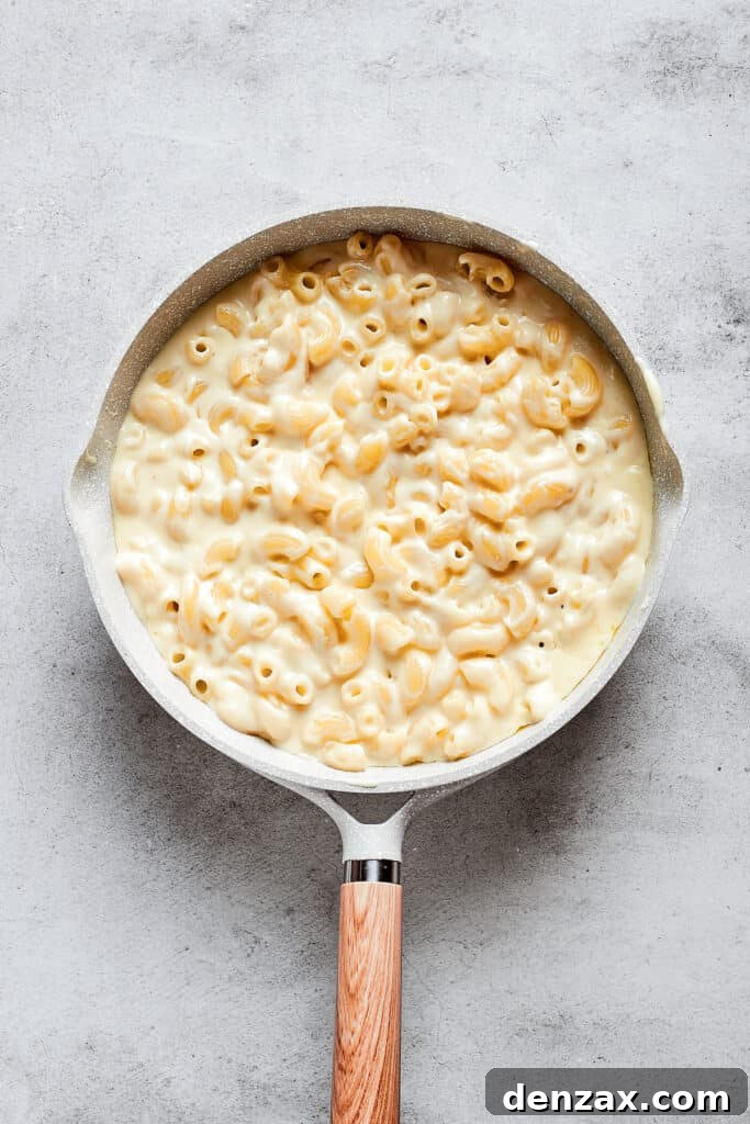 A large saucepan brimmed with perfectly cooked and mixed mac and cheese, ready for the next step.