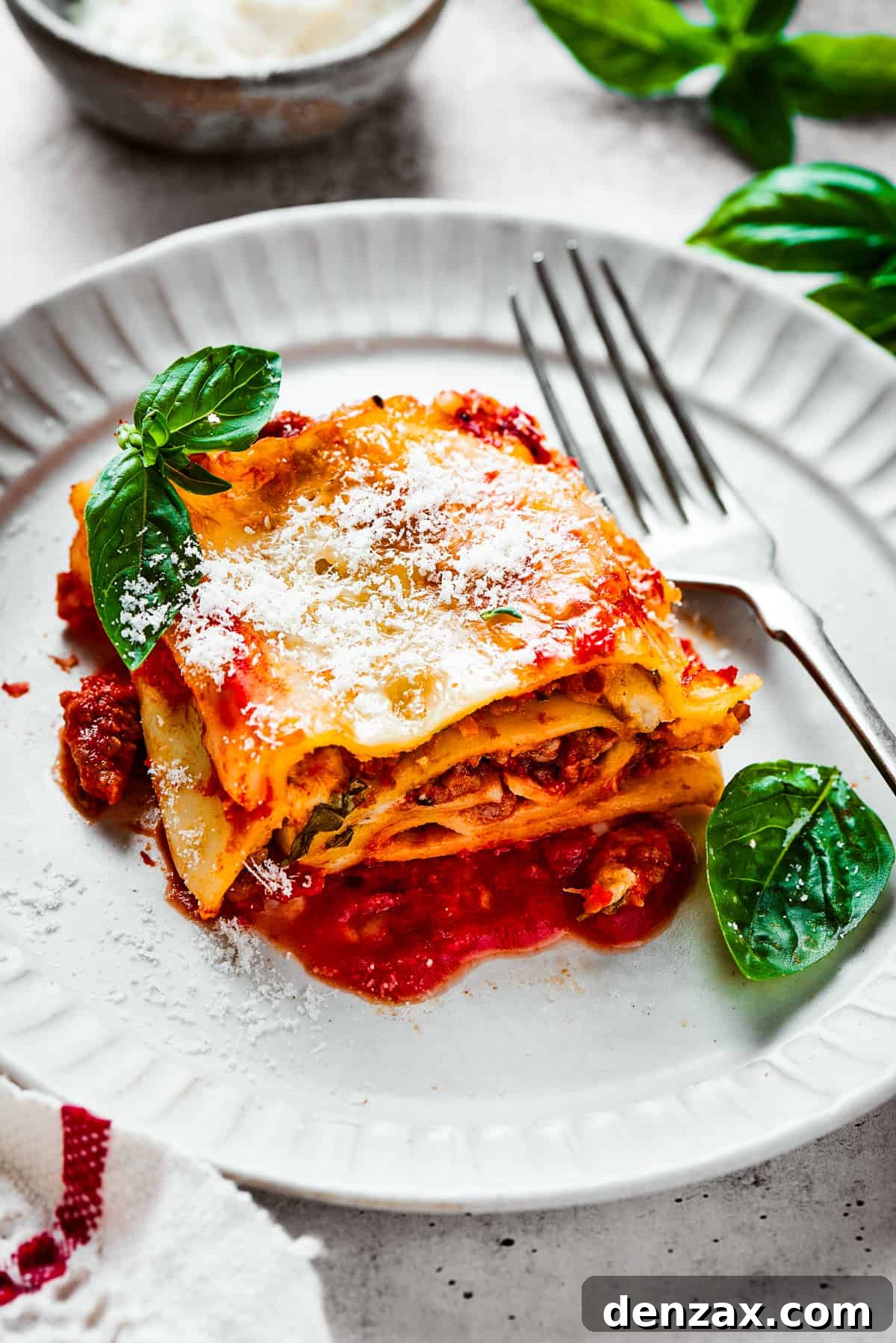 Lasagna Spirals 4 A lasagna roll on a plate with basil leaves and a fork.