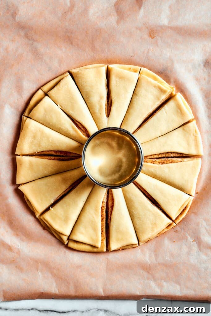 Overhead view of the star bread dough, with a glass placed in the middle as a guide, cut into 16 even segments radiating outwards.