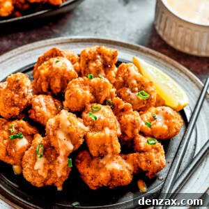 A plate of bang bang chicken with a lemon slice and a pair of chopsticks, next to a napkin and another lemon slice.