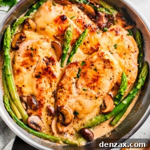 Overhead image of Chicken Madeira in a skillet with asparagus spears and mushrooms, highlighting the rich sauce and perfectly melted cheese.