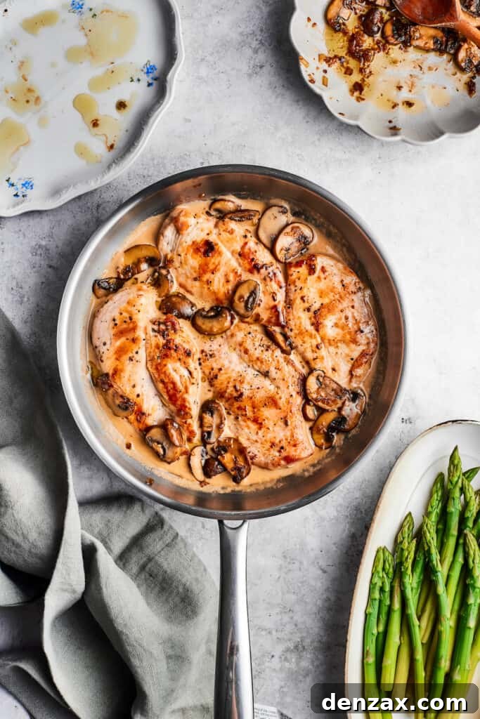 A metal skillet of chicken madeira brimming with perfectly cooked chicken, savory mushrooms, and a luscious cream sauce, ready for the final touch.