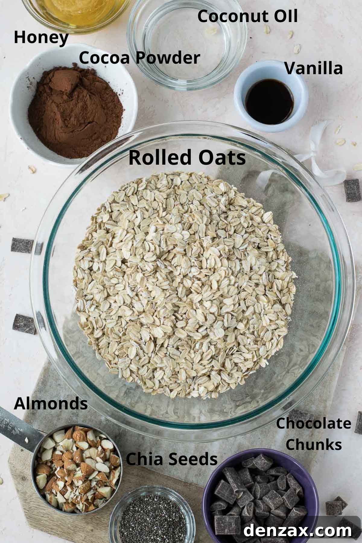 Assortment of fresh ingredients for making healthy double chocolate granola including oats, nuts, seeds, and chocolate
