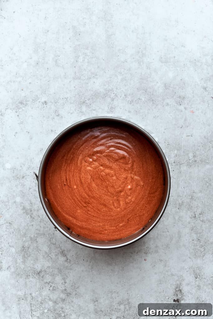 The chocolate cheesecake filling layer is smoothly spread on top of the caramel-pecan layer, adding another dimension of flavor.
