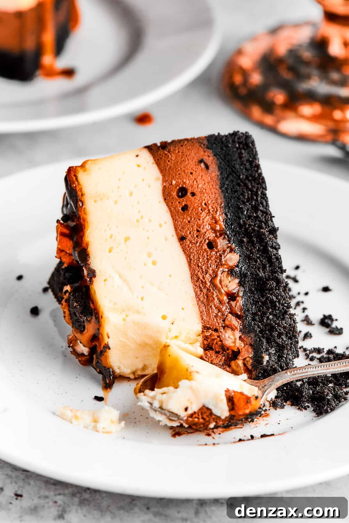 A slice of turtle cheesecake served on a dessert plate, showcasing its beautiful layers of crust, caramel, pecans, and creamy filling, topped with chocolate drizzle and nuts.