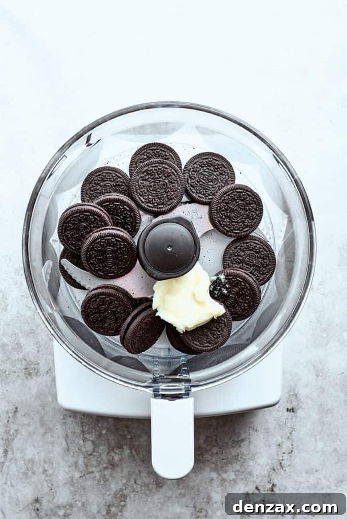 Chocolate cookies are placed in a food processor with a pat of butter, ready to be blended into a crust.