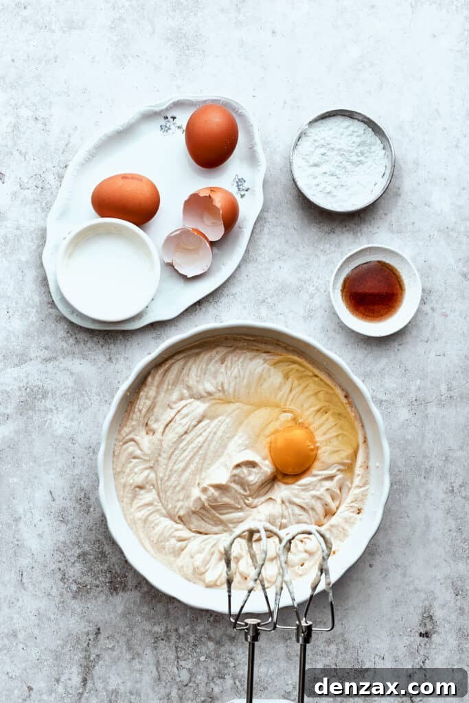 Eggs are gently mixed into a bowl of creamy turtle cheesecake batter with an electric mixer.