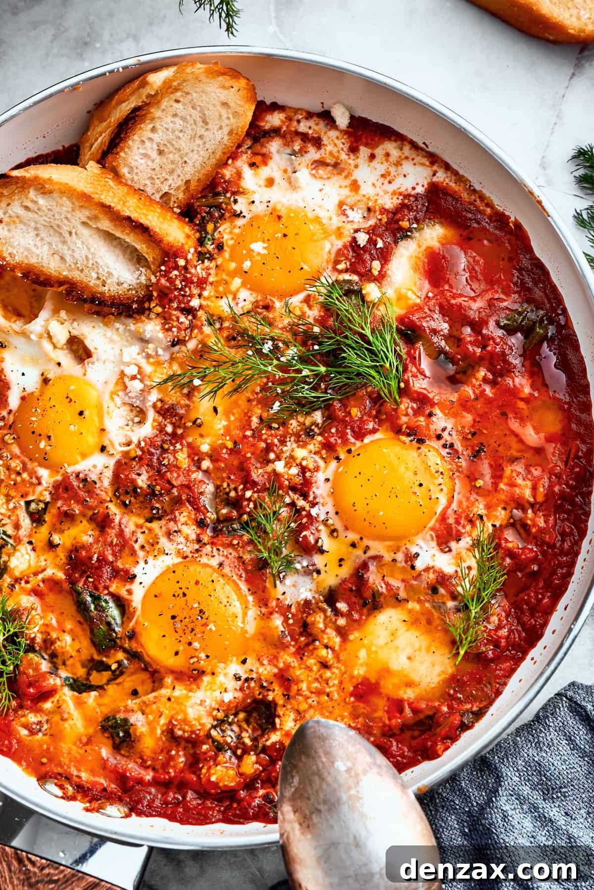 An overhead close-up shot of a skillet filled with cooked Eggs in Purgatory, beautifully garnished with vibrant fresh parsley. Several slices of golden-brown toasted bread are artfully placed around the skillet, ready for serving.