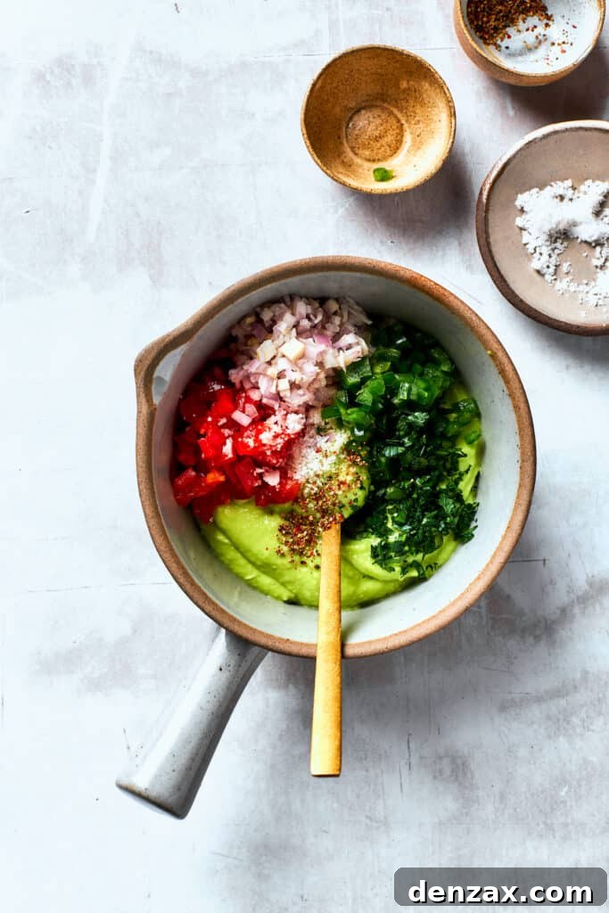 Onions, cilantro, and tomatoes are stirred into a bowl guacamole.