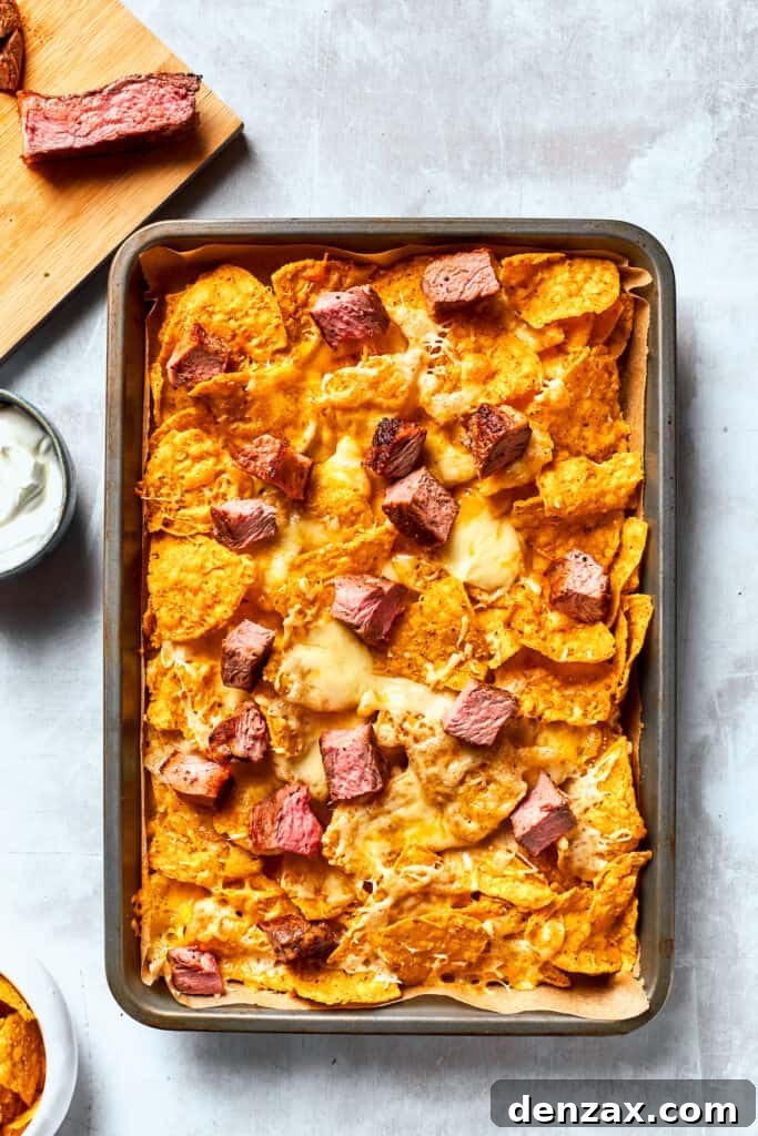 A pan of tortilla chips topped with steak and cheese.