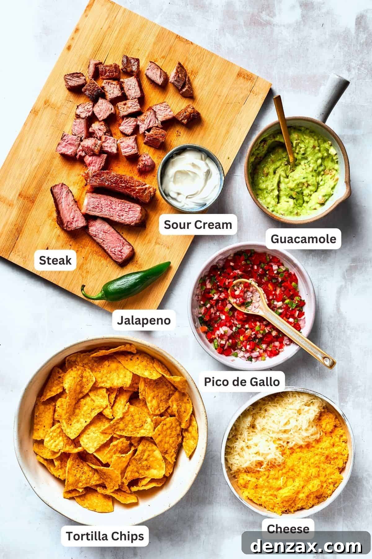 Ingredients for steak nachos are shown portioned out - guacamole, steak, pico de gallo, chips, and cheese.