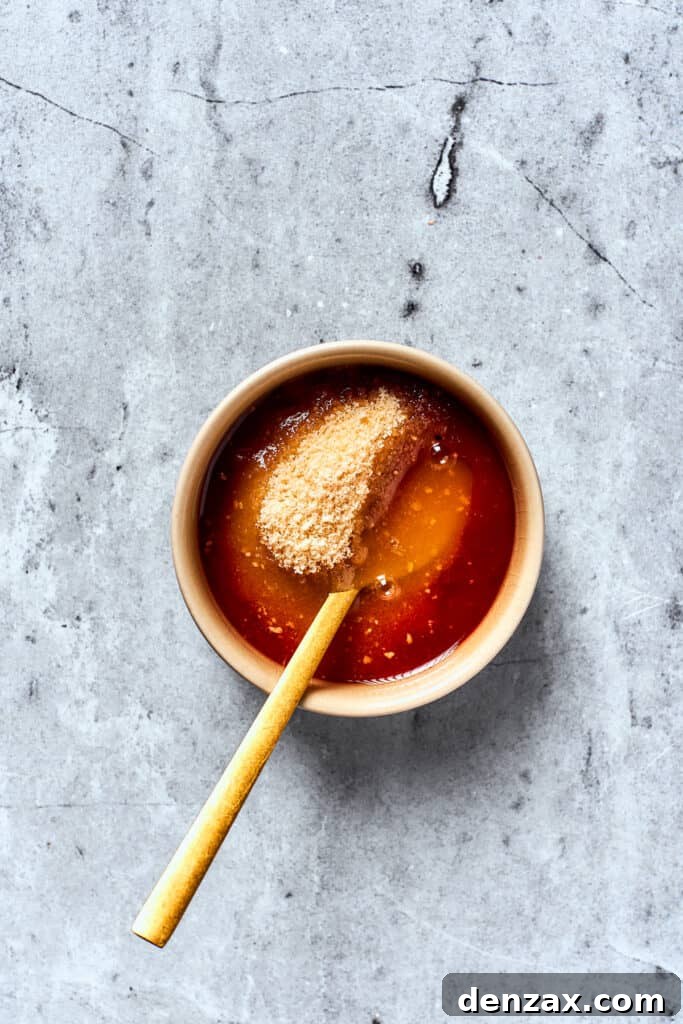 A spoon mixes brown sugar with ketchup and apple cider vinegar to make a meatloaf glaze.