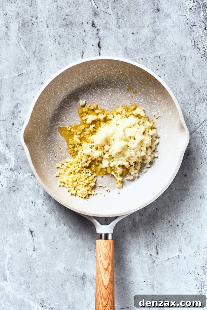 Onions and garlic cook in olive oil in a white pan.
