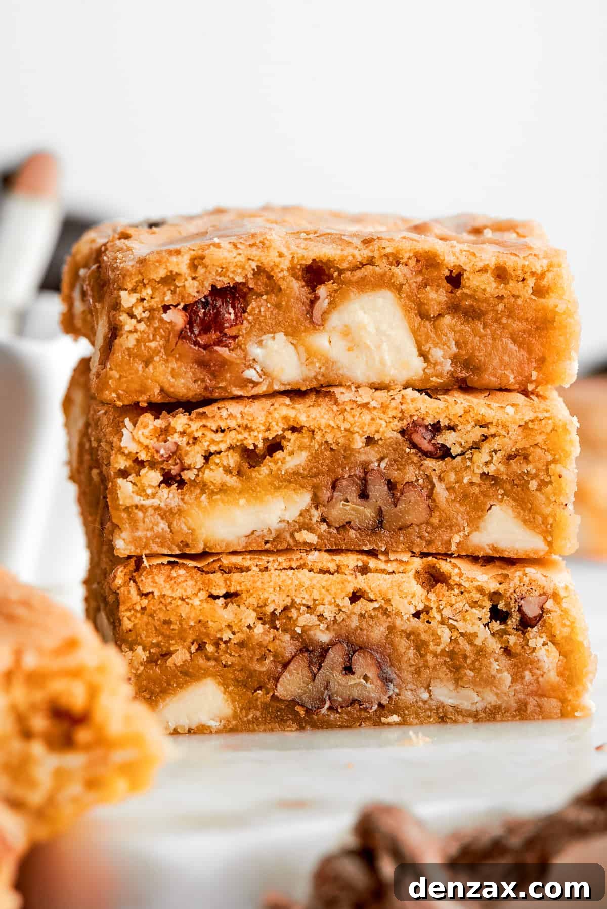 A stack of three blonde brownies with white chocolate chips and pecans visible.