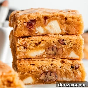 A stack of three blonde brownies with white chocolate chips and pecans visible.