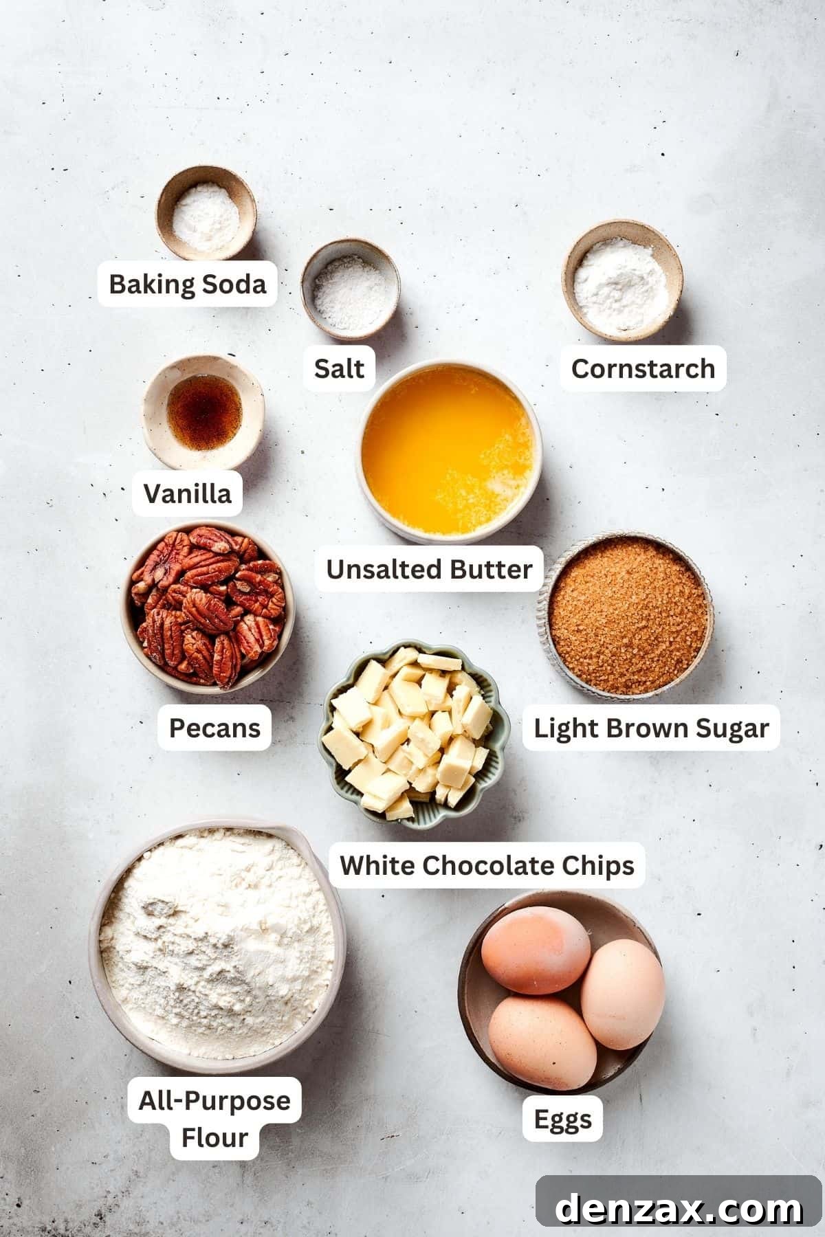 The ingredients for blonde brownies are shown portioned out: flour, cornstarch, baking soda, salt, vanilla, brown sugar, melted butter, eggs, pecans, white chocolate chips.