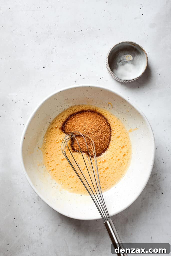 Brown sugar is added to whisked eggs.