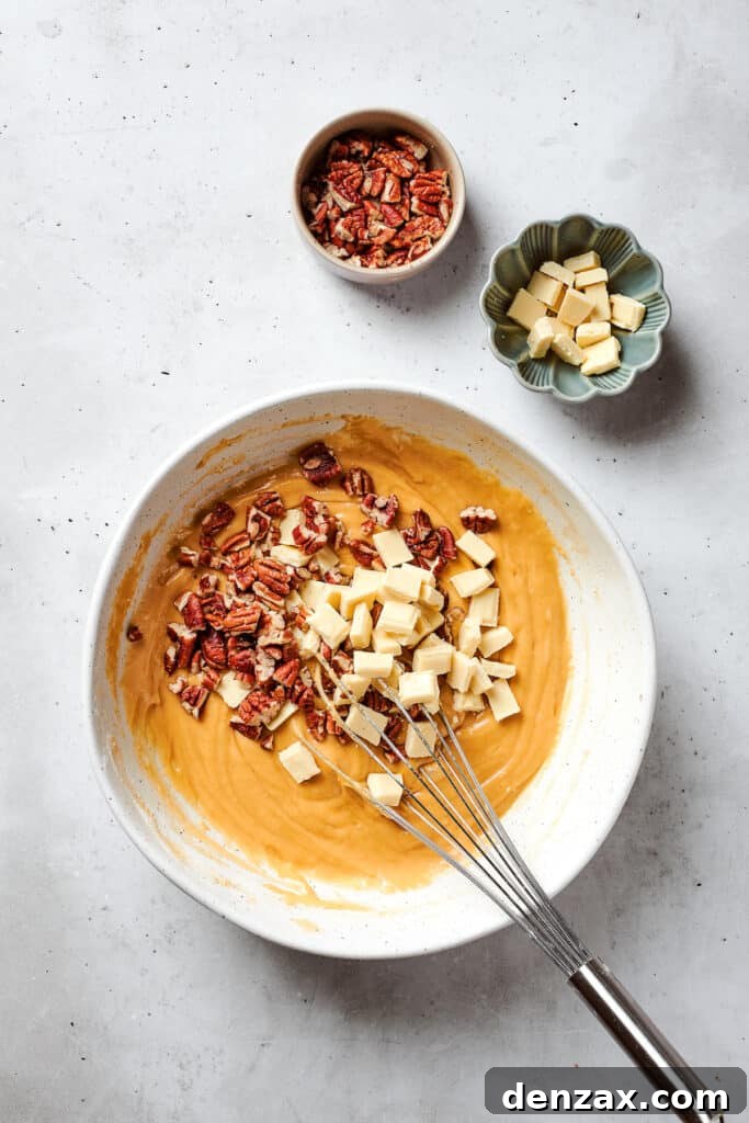 White chocolate chips and chopped pecans are stirred into a bowl of blondies batter.