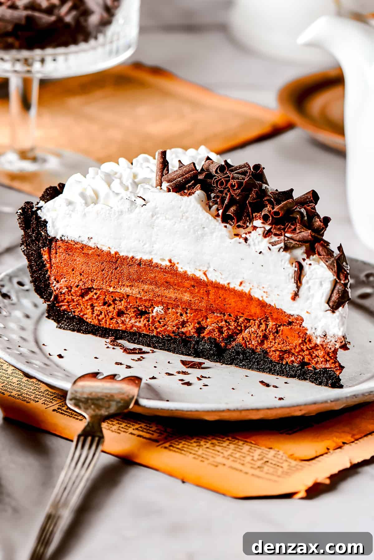 Slice of French silk pie served on a dessert plate, showcasing its rich chocolate filling and whipped cream topping.