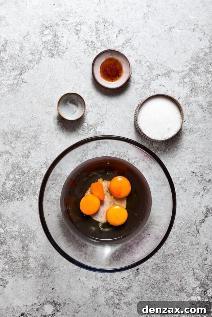 Large eggs, water, and granulated sugar are combined in a bowl, forming the base for the silky chocolate filling.