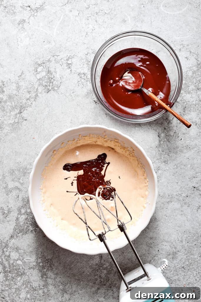 Melted chocolate is being beaten into the creamy egg mixture, creating a rich base for the French Silk Pie filling.