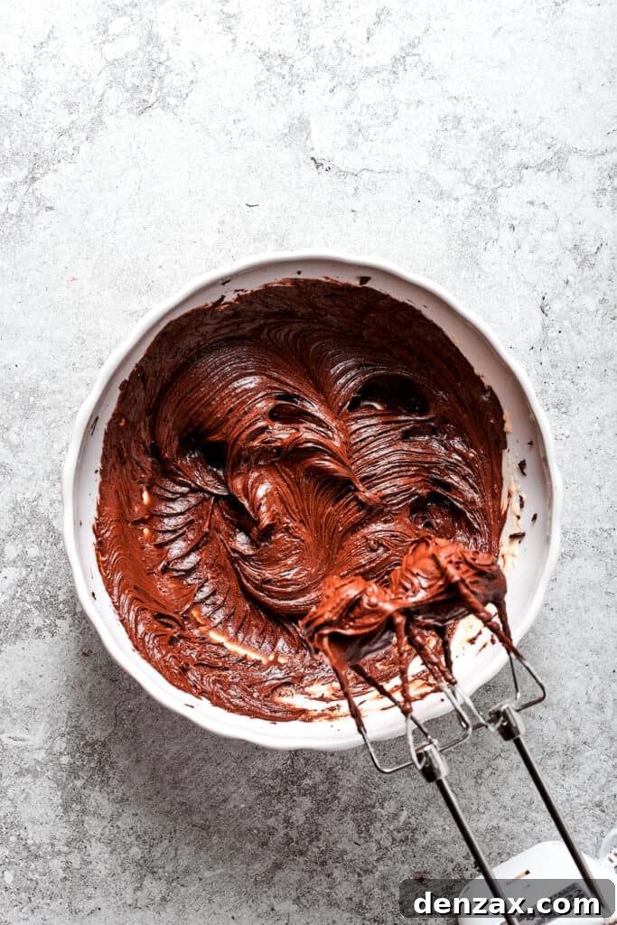 More chocolate-egg mixture is being beaten into the butter mixture, ensuring a smooth, homogenous filling.