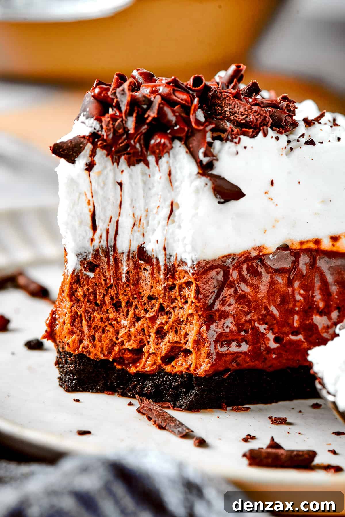 A perfectly portioned piece of French silk pie on a white plate, with a fork ready to enjoy a bite of the layered dessert.
