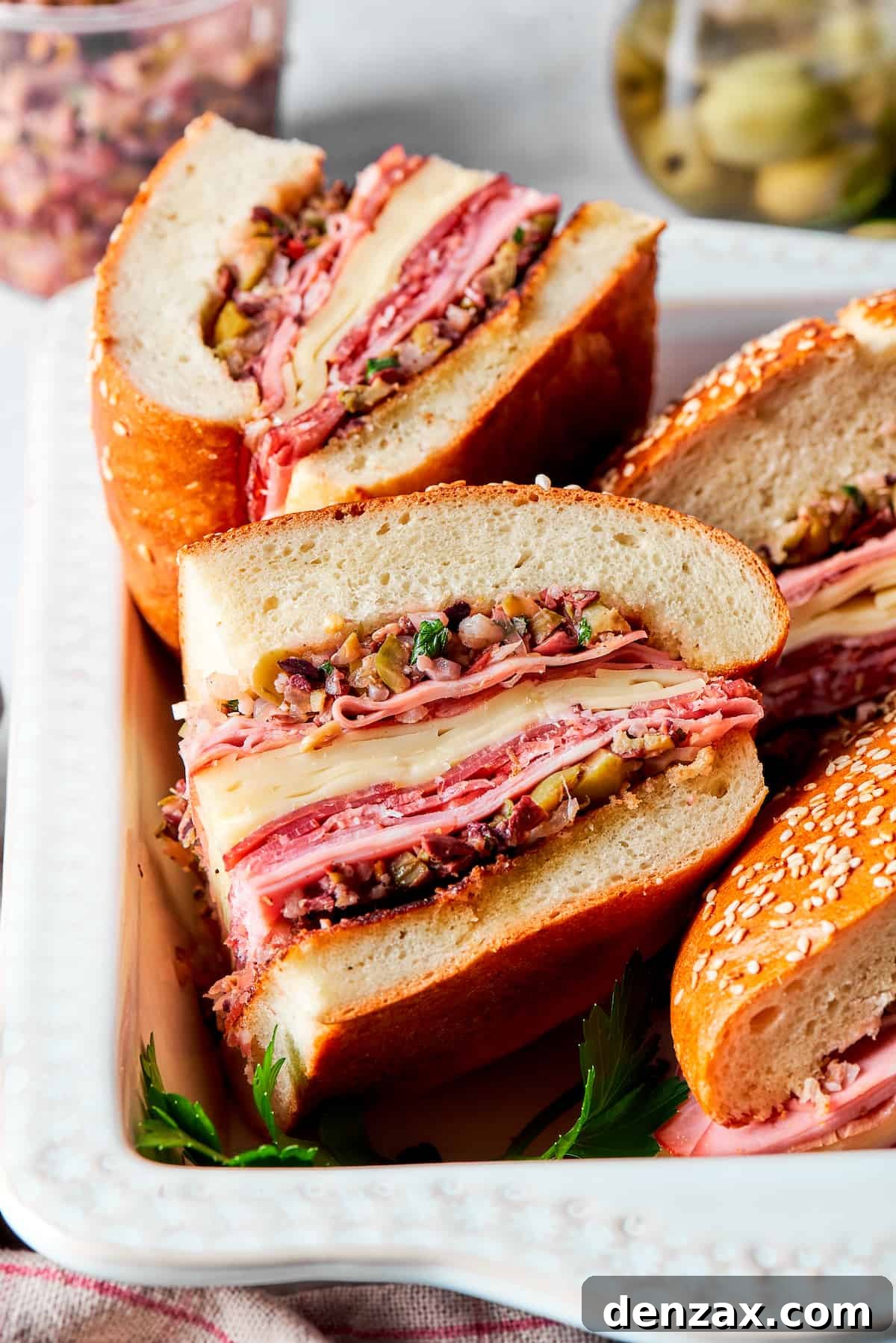 Several perfectly cut slices of muffaletta sandwich are artfully displayed on a cutting board, highlighting the impressive layers of meats, cheeses, and olive salad, ready for serving.