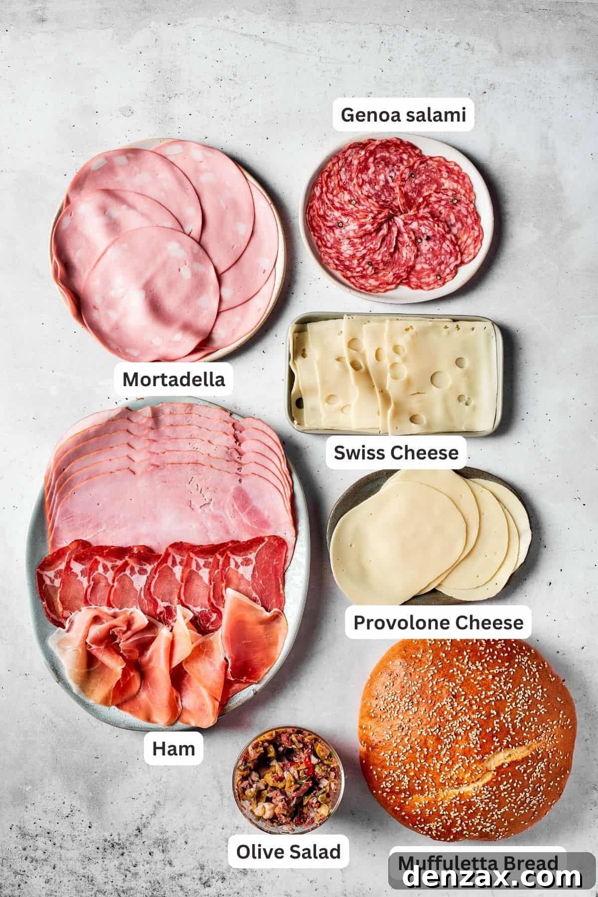 An appetizing arrangement of thinly sliced mortadella, capicola ham, genoa salami, provolone cheese, swiss cheese, and a small bowl of fresh olive salad, all prepared for assembling a gourmet muffaletta sandwich.