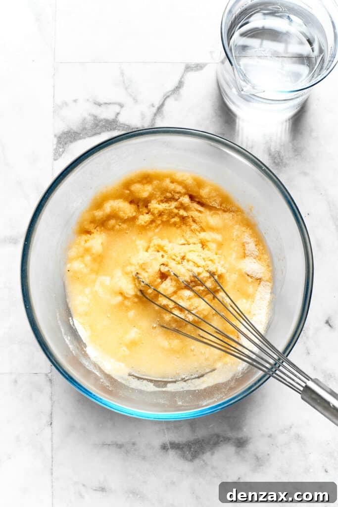 A whisk vigorously combines dry ingredients for Spoon Bread batter in a large mixing bowl.