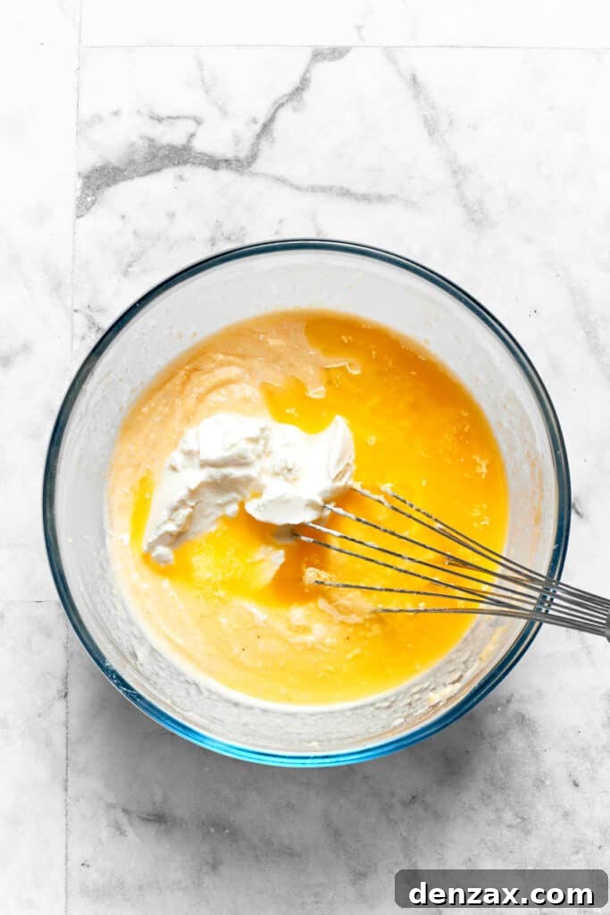 A generous dollop of sour cream is being mixed into the Spoon Bread batter, adding richness and tang.