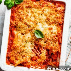 Basil leaves garnish a white baking dish of chicken parmesan casserole.