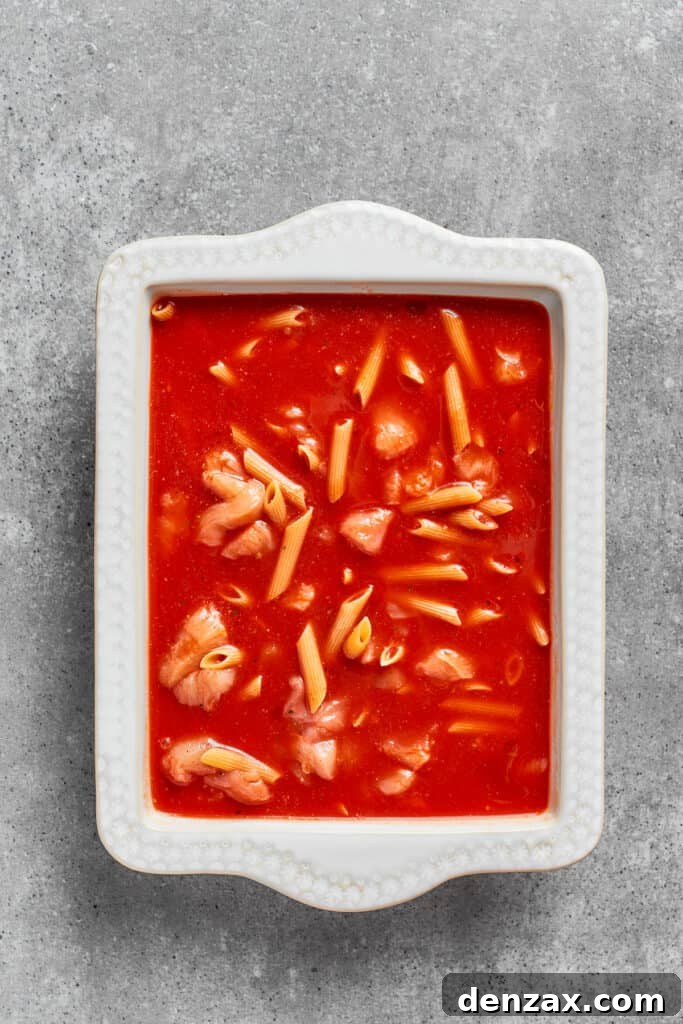 Pasta is added to the sauce in the baking dish.