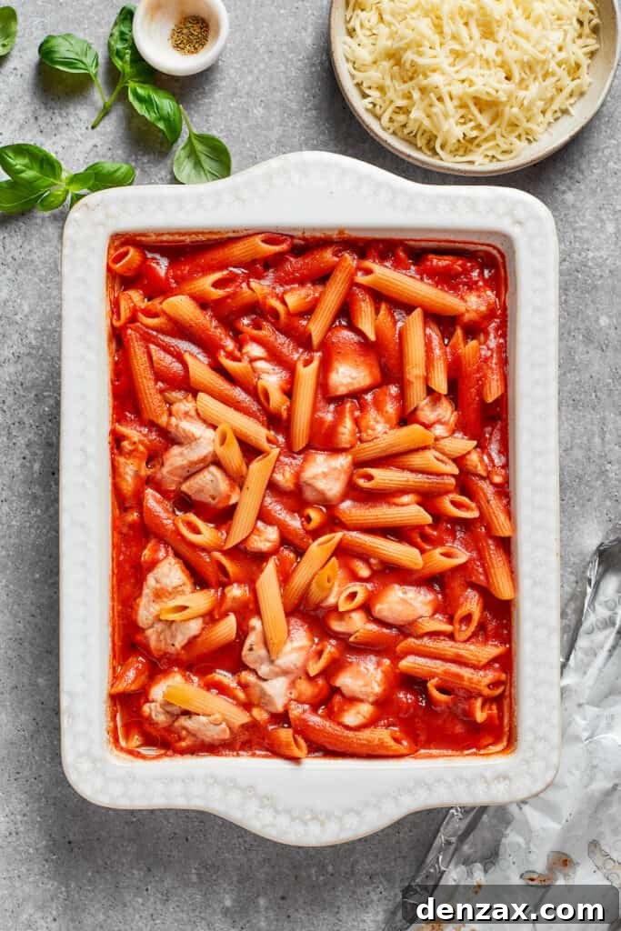 The sauce, pasta, and chicken are added to the baking dish.