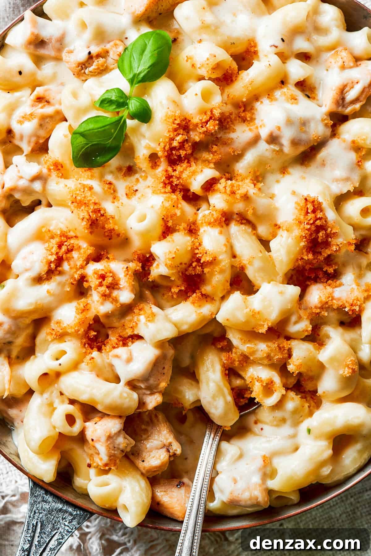 Close-up image of macaroni and cheese in a bowl, with a spoon stirring through it.