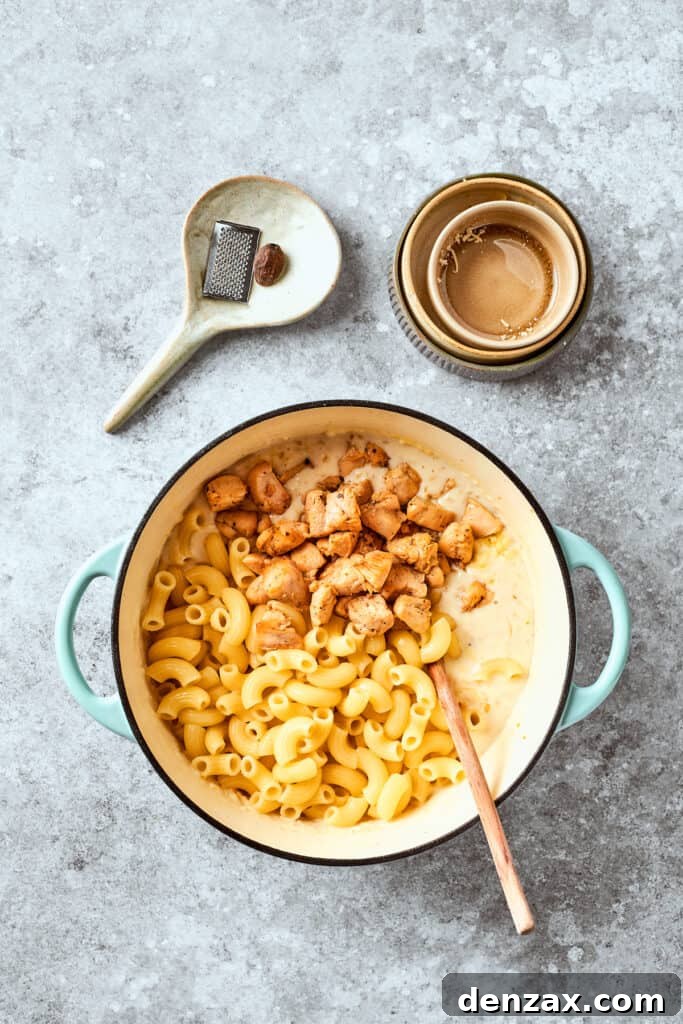 Chicken is stirred into the pasta.