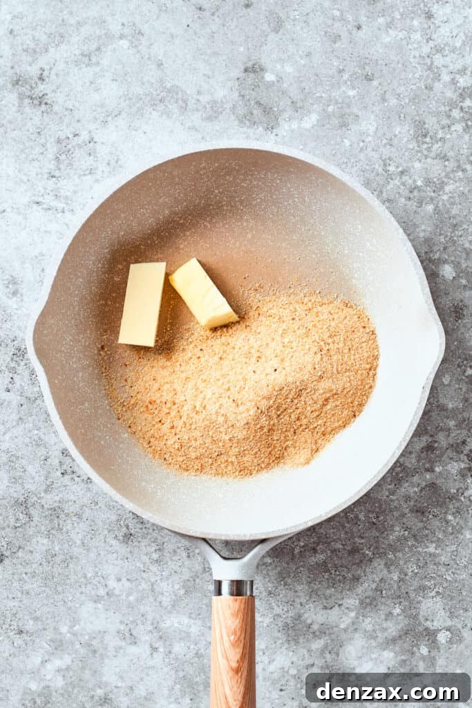 Butter is added to breadcrumbs in a pan.